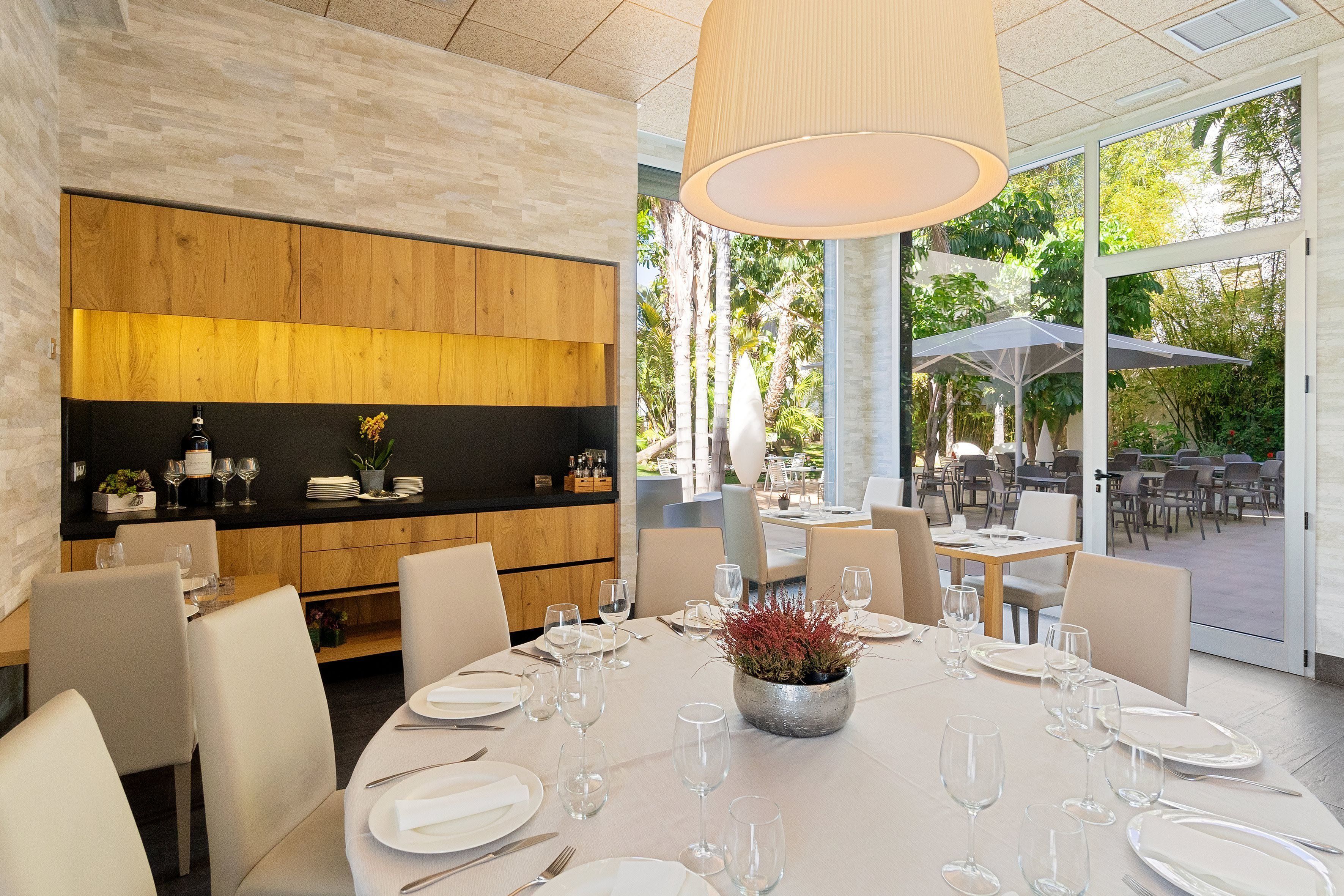 A modern dining area with a central round table set for a meal, surrounded by chairs, and a wooden accent wall.