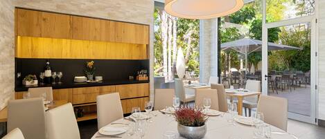 A modern dining area with a central round table set for a meal, surrounded by chairs, and a wooden accent wall.