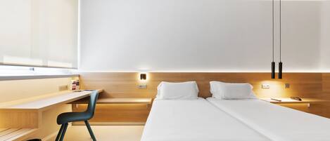 Una habitación de hotel moderna con cabecera de madera, un escritorio con silla, dos camas y un ventanal grande.