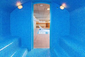 An indoor swimming pool with blue tiled walls and a wooden floor.