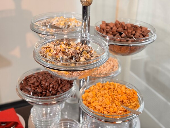 A multi-tiered glass display stand with various food items.