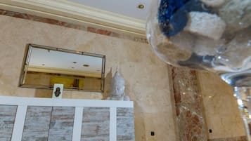 A marble wall with a framed mirror, a statue, and a decorative glass object.