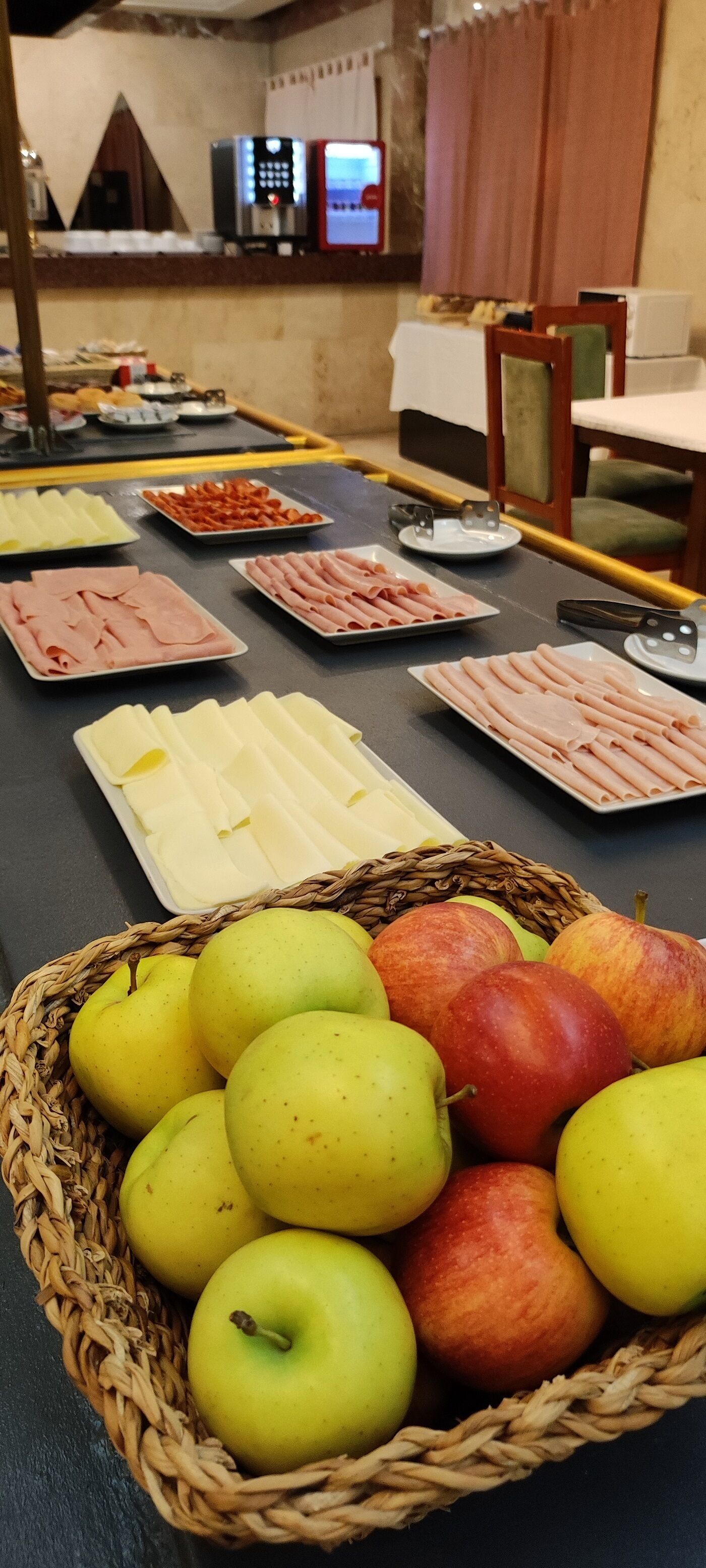 A buffet table with various food items including sliced meats, cheeses, and fruits.