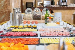 Un buffet proposant une variété de plats, notamment des viandes, des fromages et des œufs.