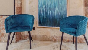 A room with two teal velvet chairs, a marble wall, and a large abstract painting. - Hotel Aeropuerto Sur (Granadilla de Abona)