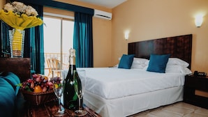 A hotel room with a bed, a nightstand, a table with a bottle and glasses, a chair, and a window with curtains. - Hotel Aeropuerto Sur (Granadilla de Abona)