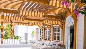 An outdoor patio with wooden pergolas, stone flooring, and outdoor seating.