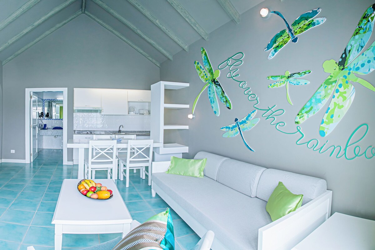 A modern hotel room with a kitchen, dining area, and living space.