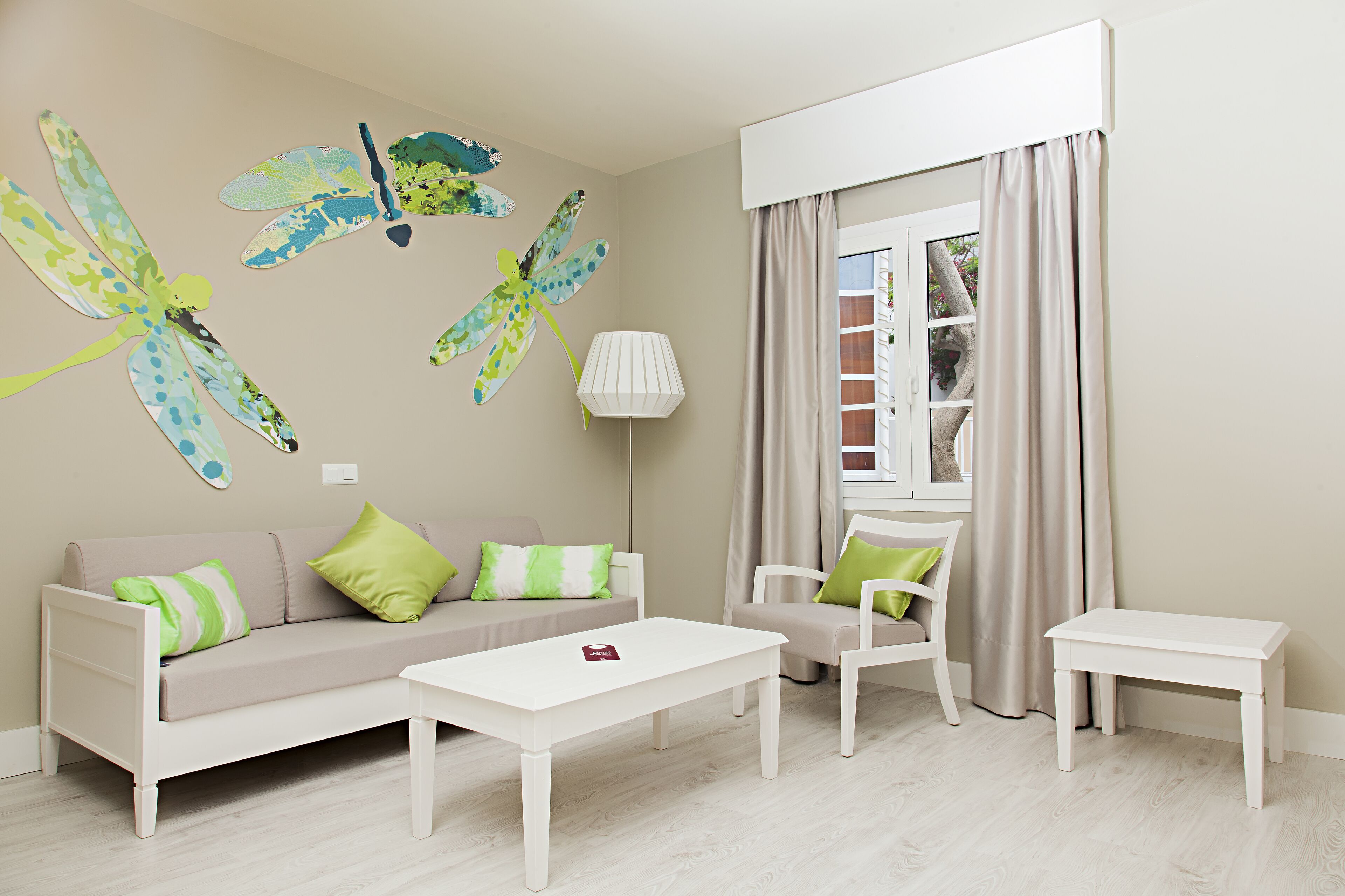 Una sala de estar moderna con un sofá, dos sillones, una mesa de centro y un ventanal con cortinas.
