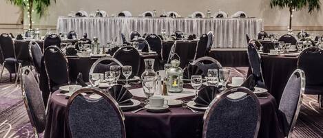 A banquet hall with round tables set for dining, each with chairs and table settings.