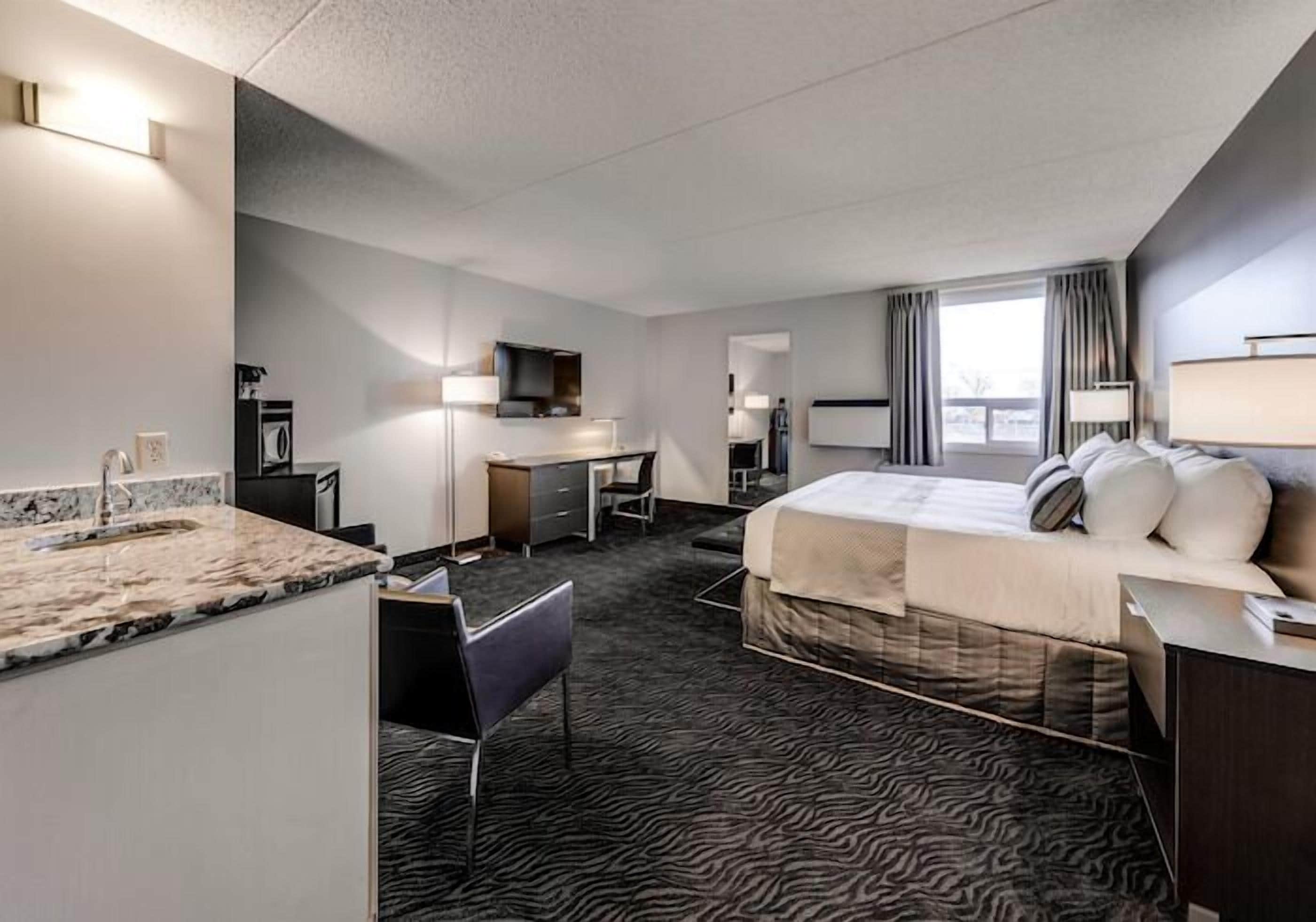 Ein Hotelzimmer mit Bett, Schreibtisch, Stuhl und Blick auf die Stadt.