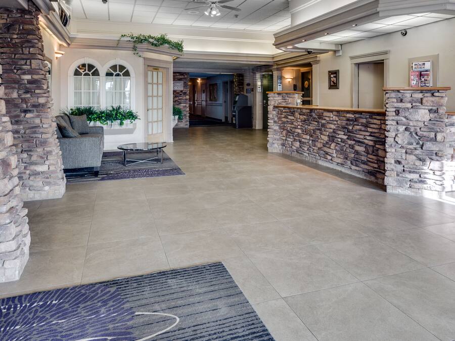 Eine geräumige Lobby mit einem Steinschrever, einer Sitzecke mit einer Couch und Sesseln sowie einem großen Teppichboden.