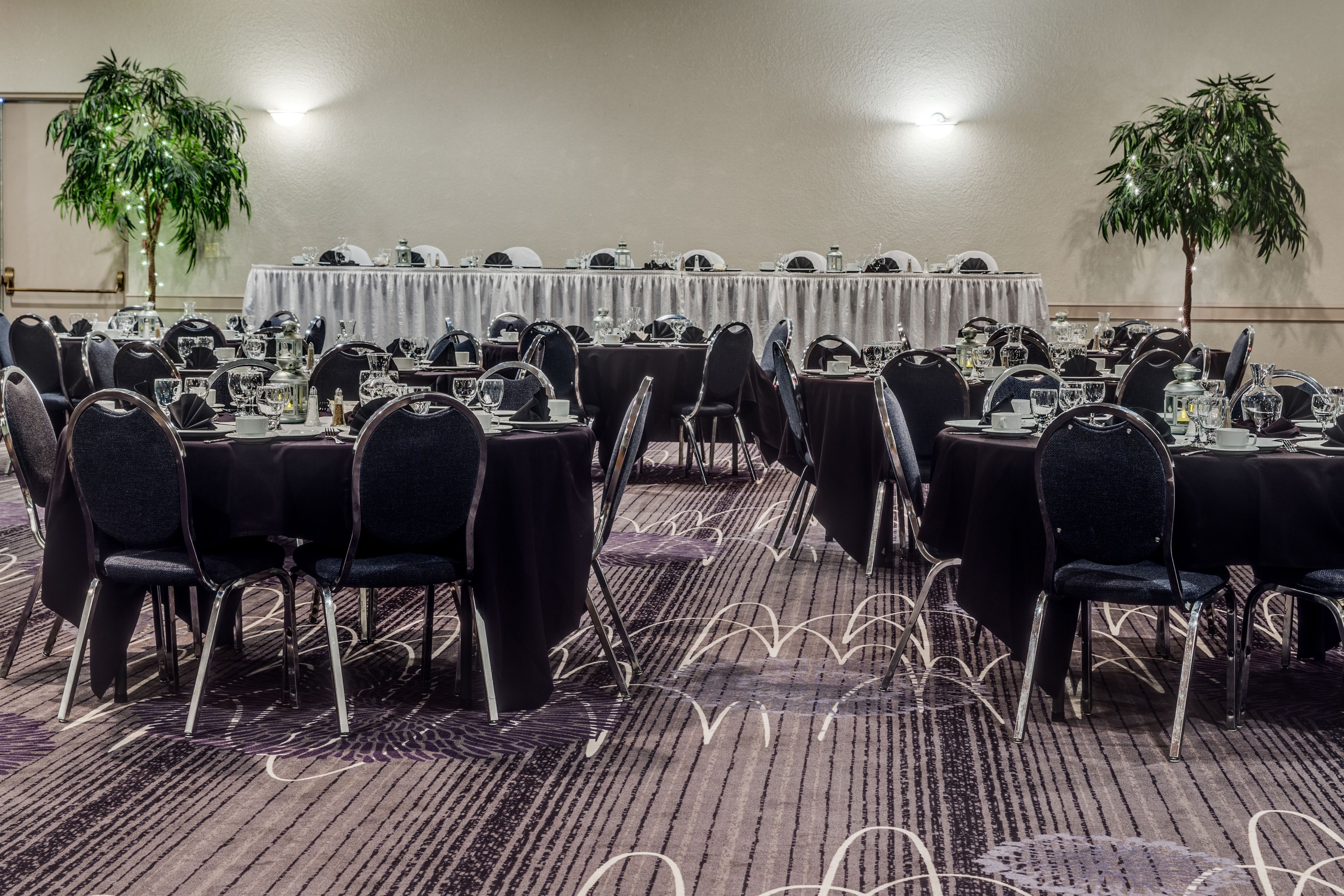 A conference room with round tables, black chairs, and a carpeted floor.
