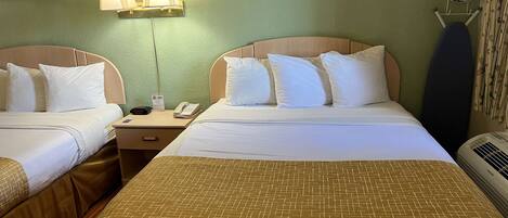 A hotel room with two beds, a nightstand, a lamp, an iron, and a wall-mounted picture.