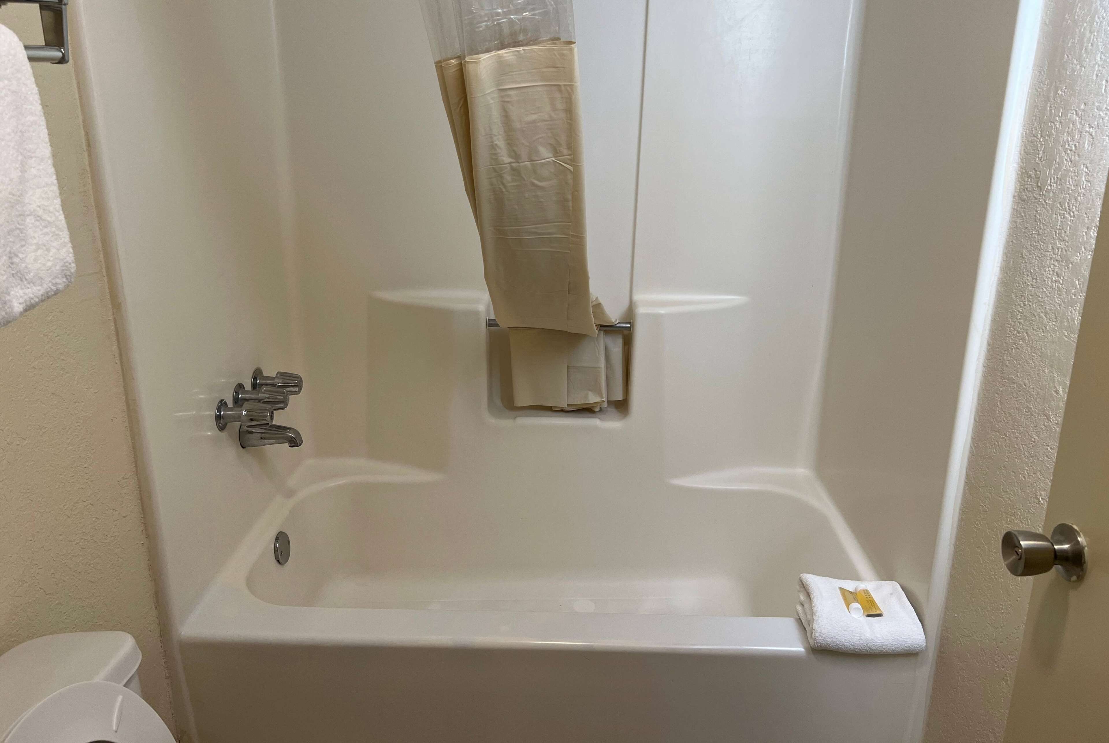 Et badeværelse med badekar, toilet og håndklædetørrestativ.