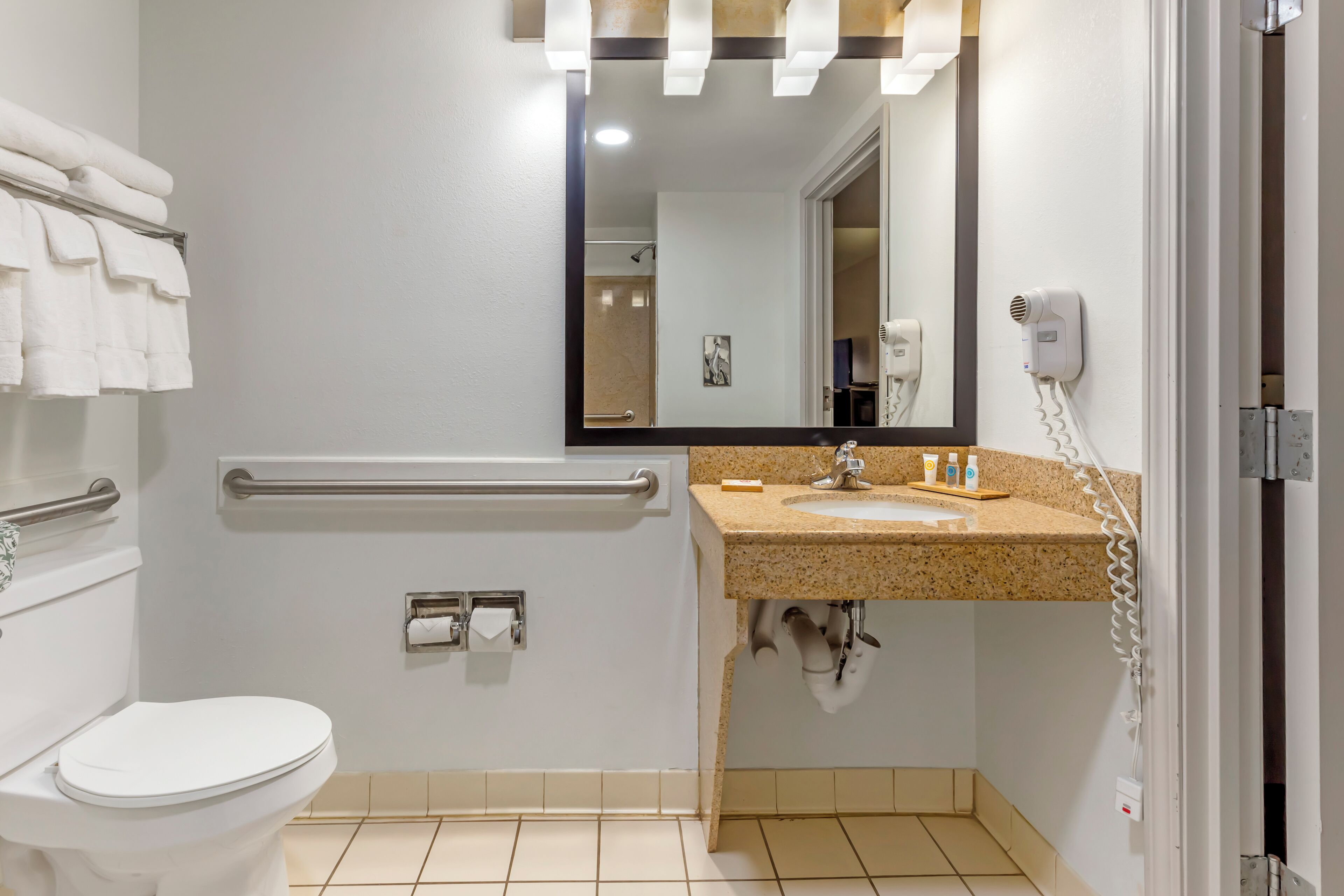 Un baño moderno con inodoro, barandilla, lavamanos y espejo.