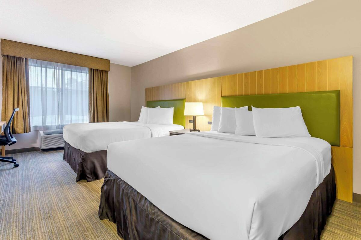 Habitación de hotel con dos camas, un escritorio y una silla.