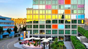 A Radisson hotel with a modern glass facade, a landscaped outdoor area with seating, and a clear sky.