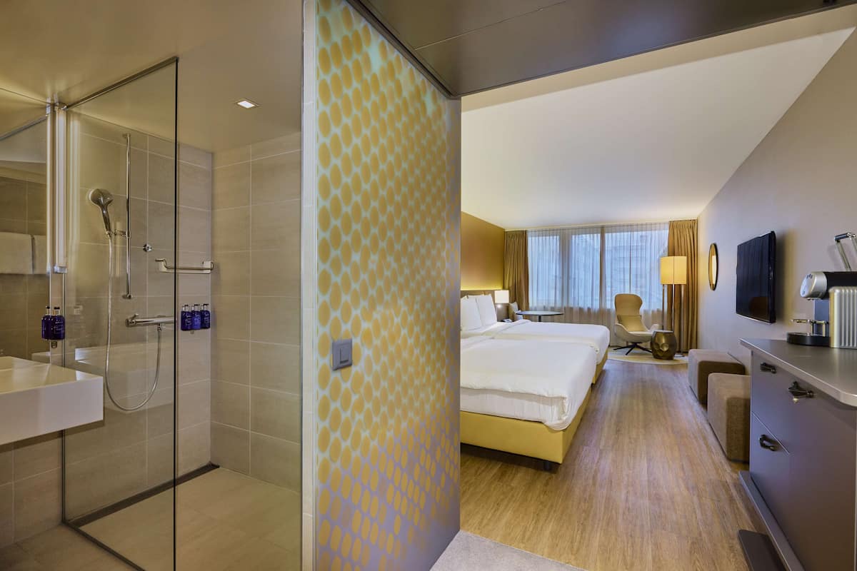 A hotel room with a shower, a bed, a desk, and a TV.