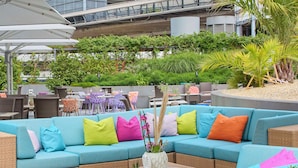 A modern outdoor seating area with a blue sofa, colorful cushions, and a glass-top table. - Radisson Blu Hotel, Lucerne (Lucerne)