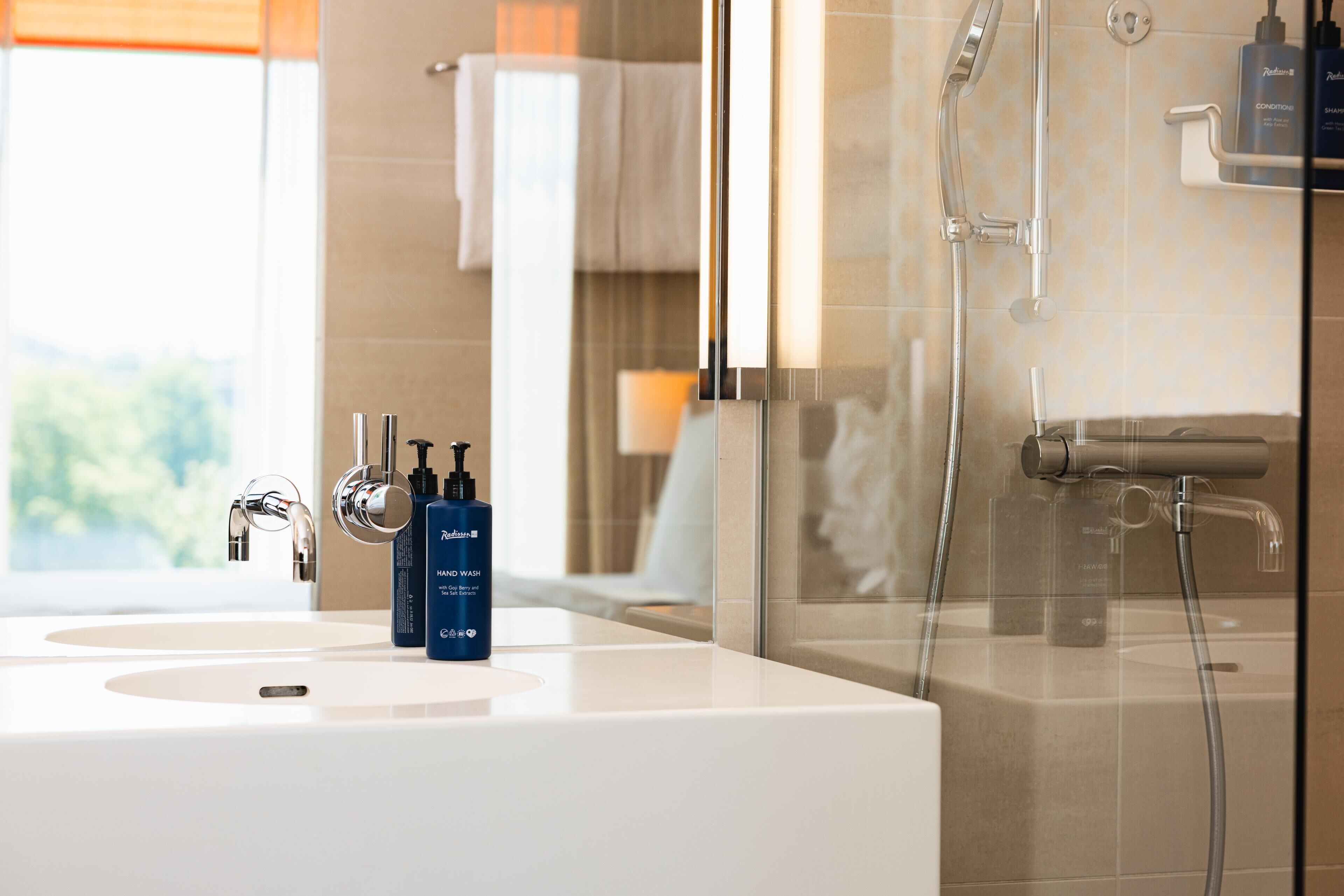 Un baño moderno con un espejo grande, dos lavamanos y una zona de ducha.