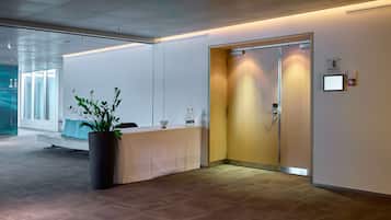 Welcome to our hotel lobby, featuring a reception desk, elevator, and a touch of greenery.