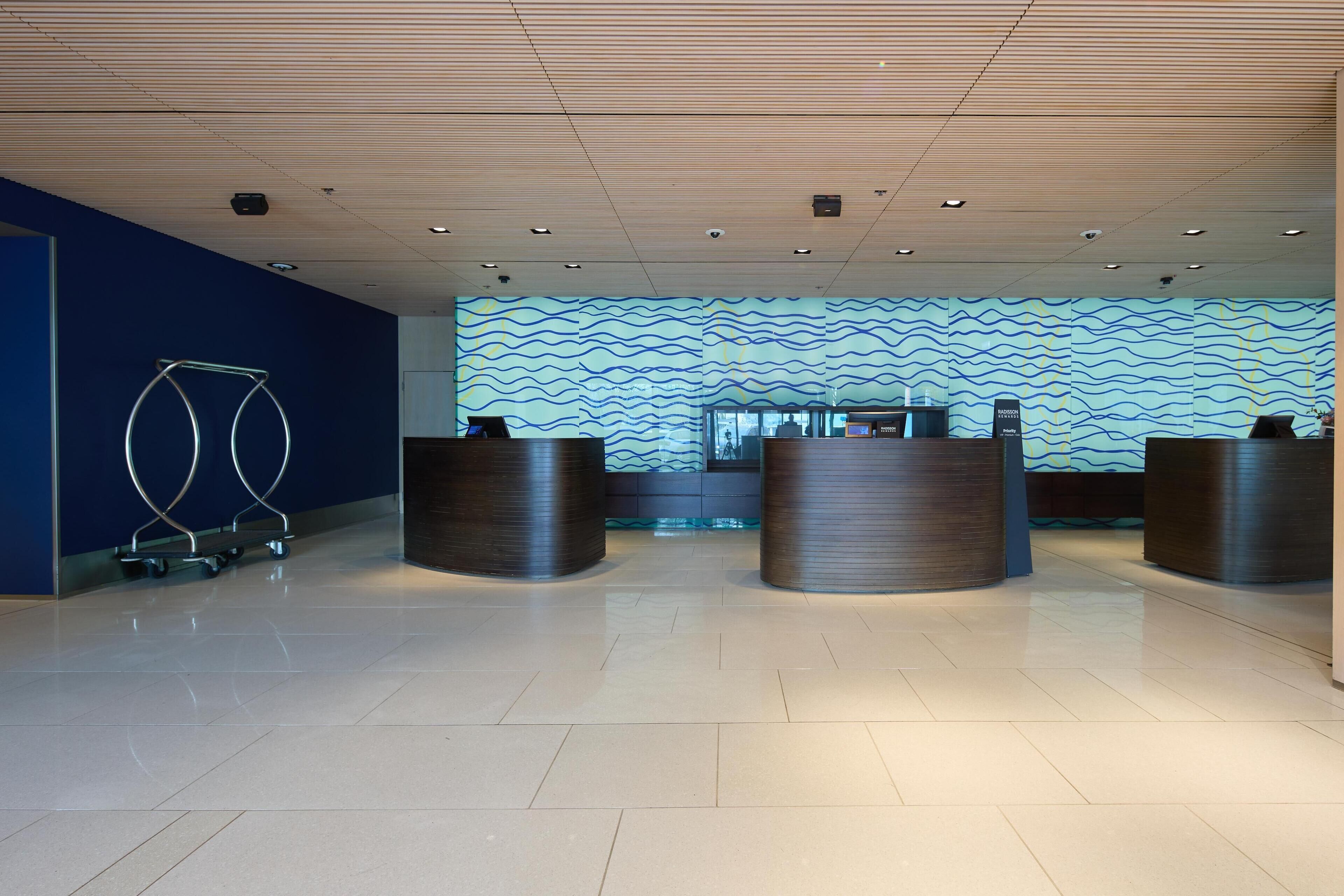 A modern reception area with a wavy blue wall design, a clean tiled floor, and a reception desk.