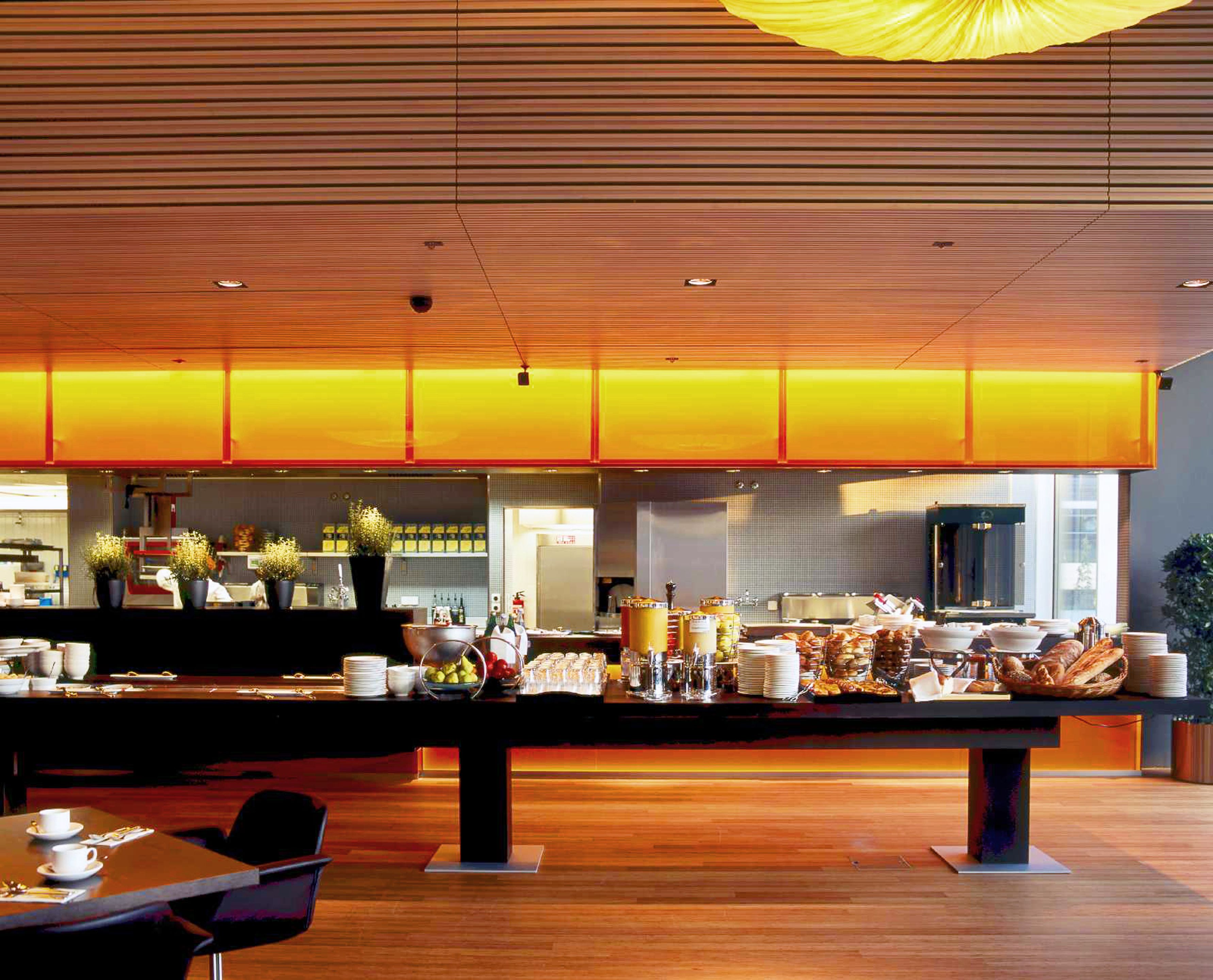 Un bufé de desayuno moderno con techo de madera y una pared de acento amarillo brillante.