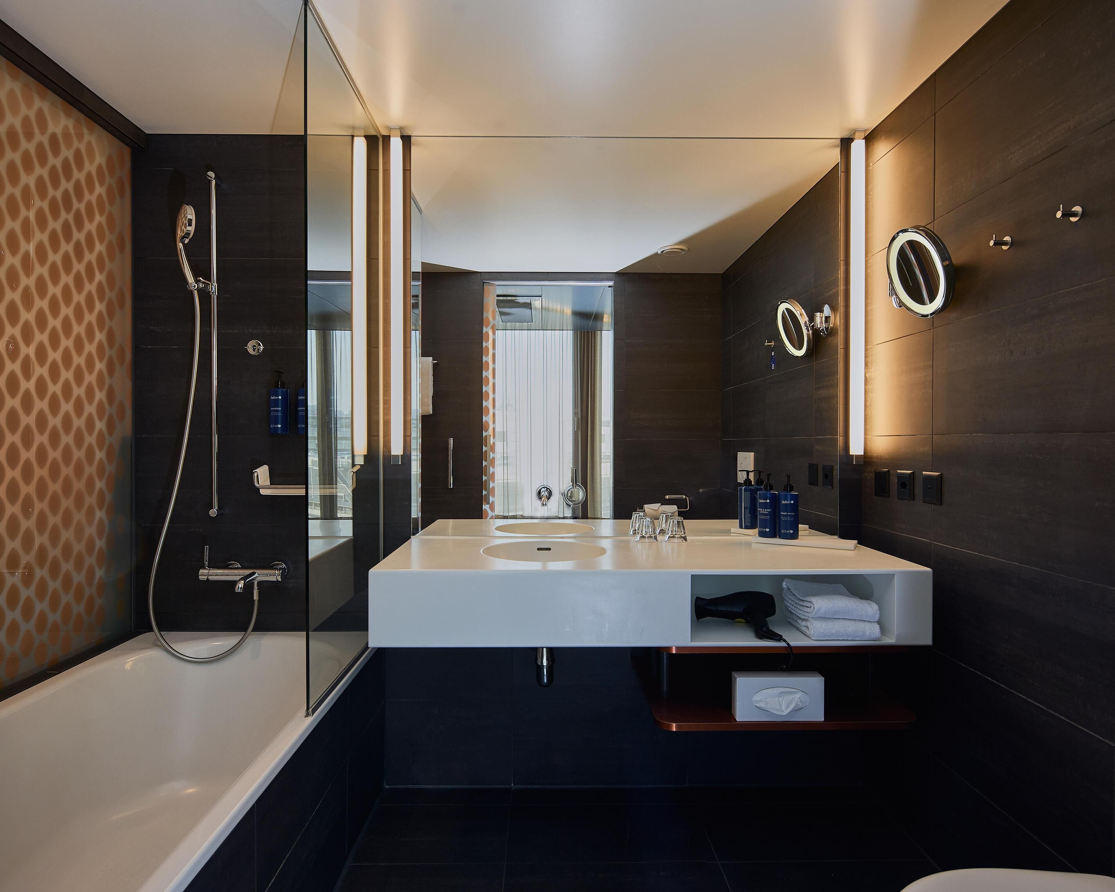 Ein modernes Badezimmer mit einem großen weißen Waschbecken, einer gläsernen Dusche und dunkelholzvertäfelten Wänden.
