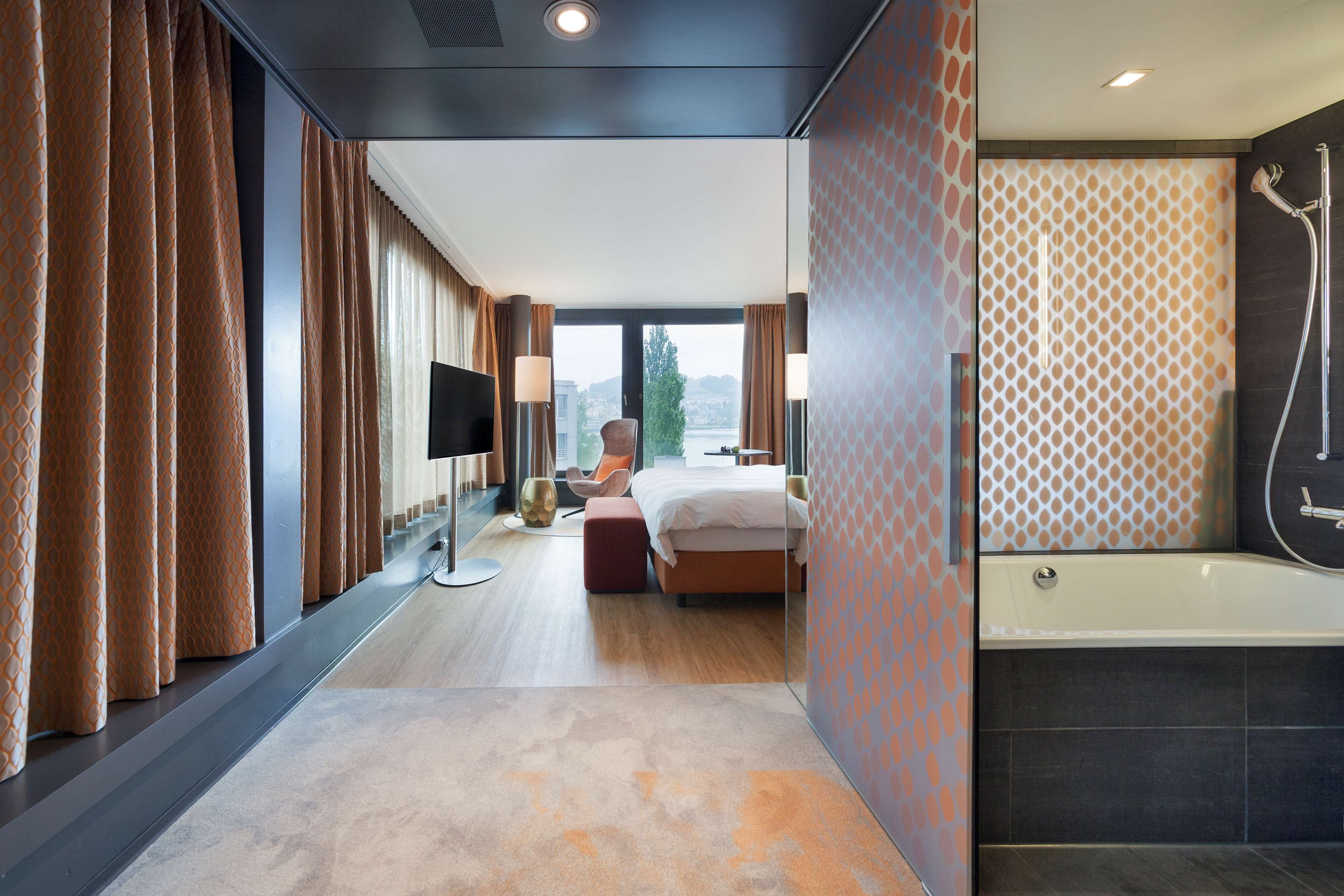Une chambre d’hôtel moderne avec un grand lit, une télévision et une douche.