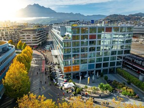 A modern building with a glass facade, surrounded by a landscaped area with trees and a small plaza. - Radisson Blu Hotel, Lucerne (Lucerne)
