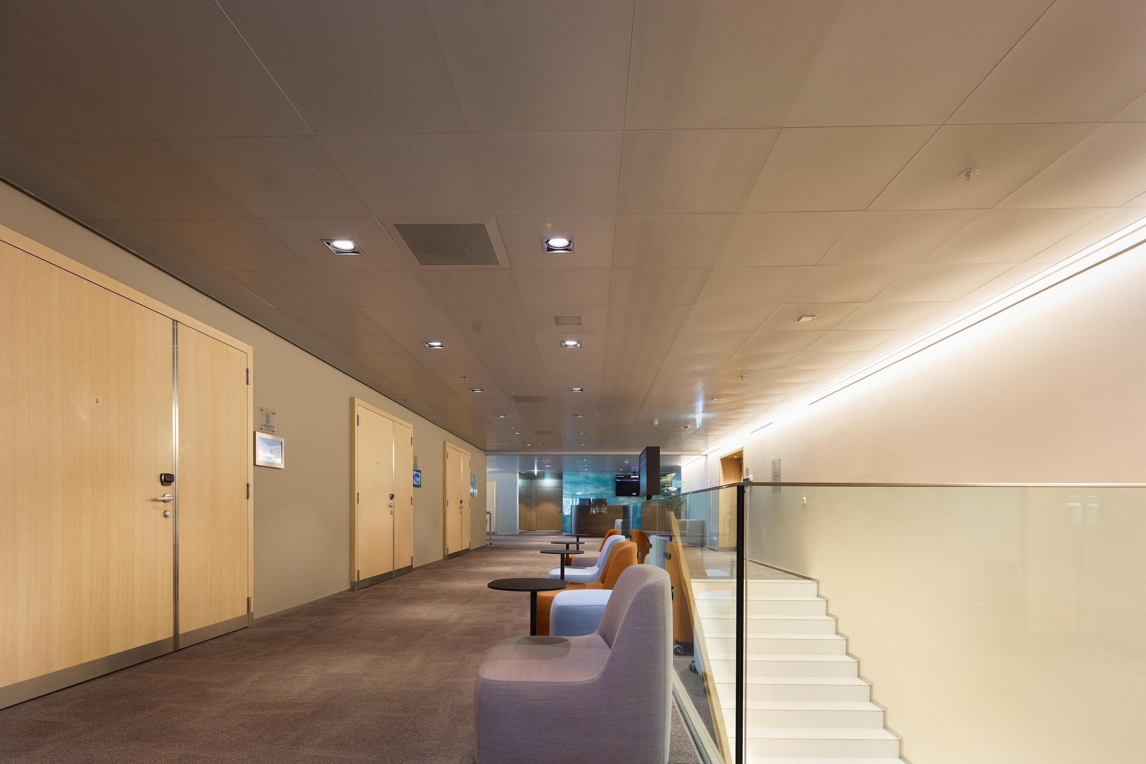 A hallway with wooden lockers, seating areas, and a staircase.