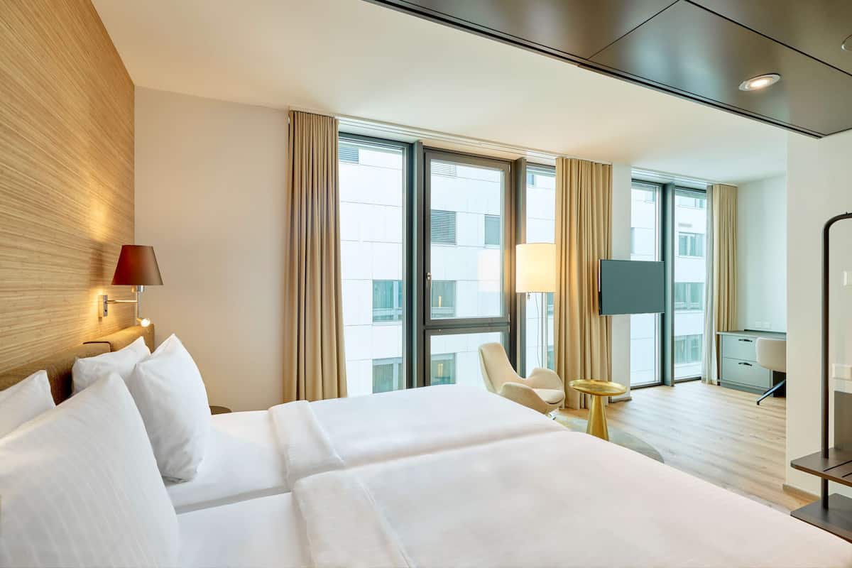 A hotel room with a large bed, a desk, a chair, and a TV.
