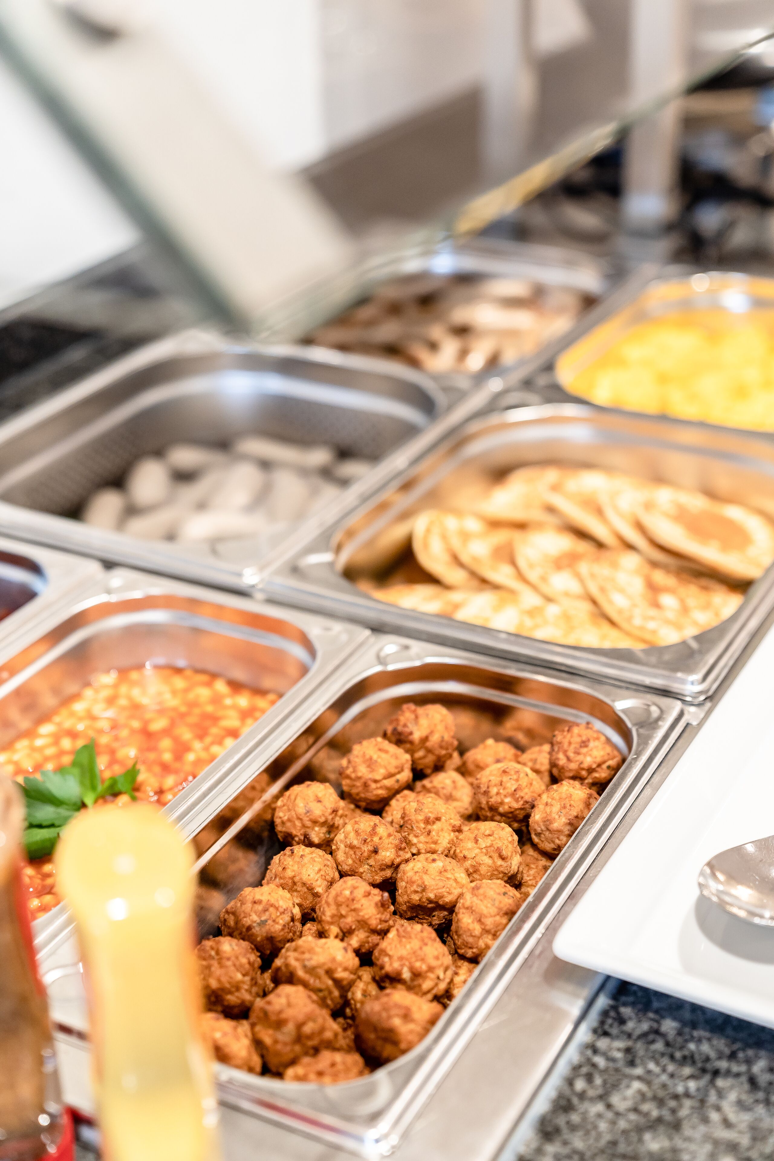 Un buffet con diversi piatti, tra cui polpette, pancake e altre specialità.