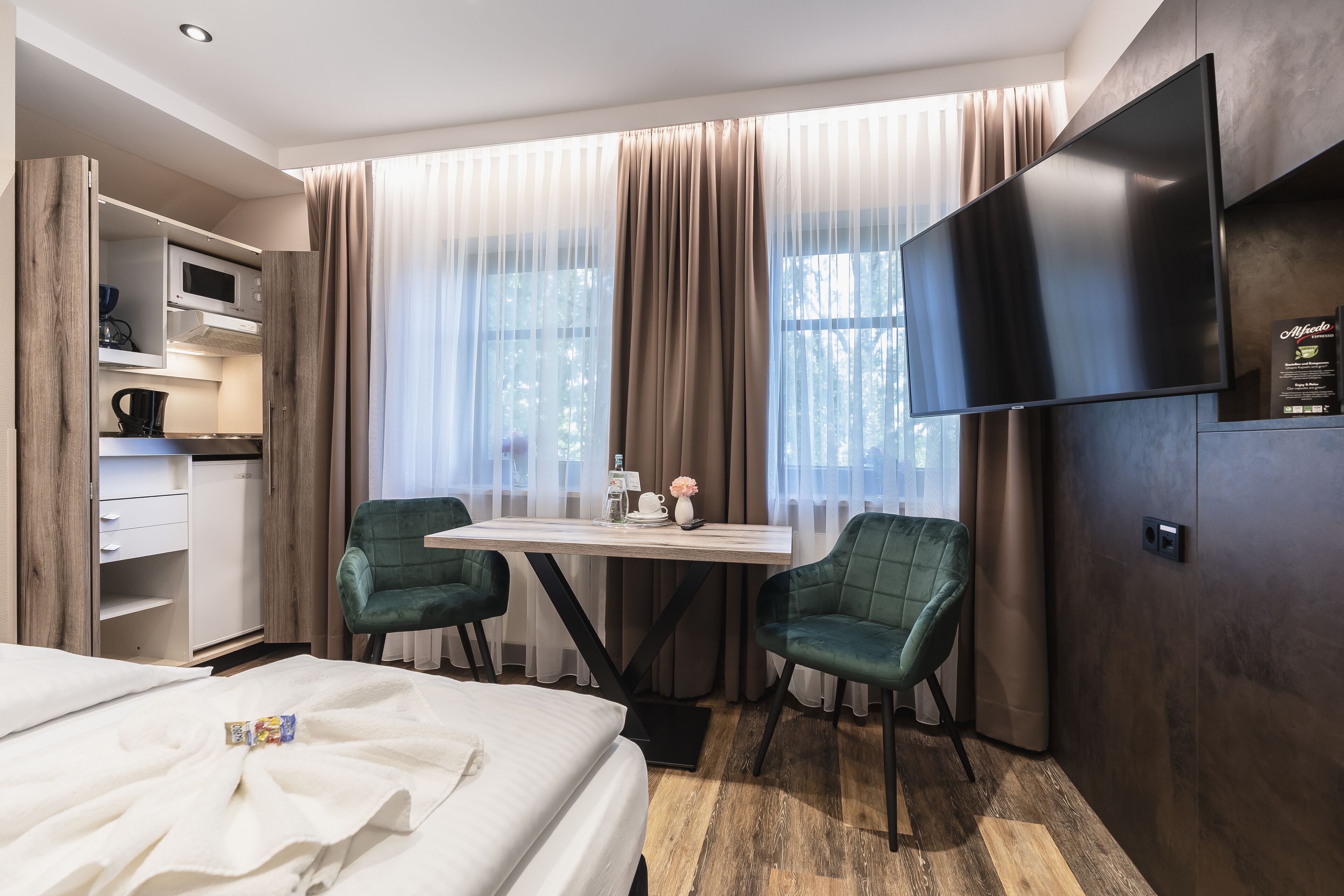 Een hotelkamer met een bed, een bureau met stoel, een televisie en een kledingkast.