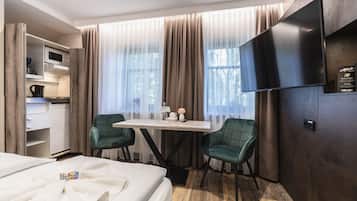 Een hotelkamer met een bed, een bureau met stoel, een televisie en een kledingkast.