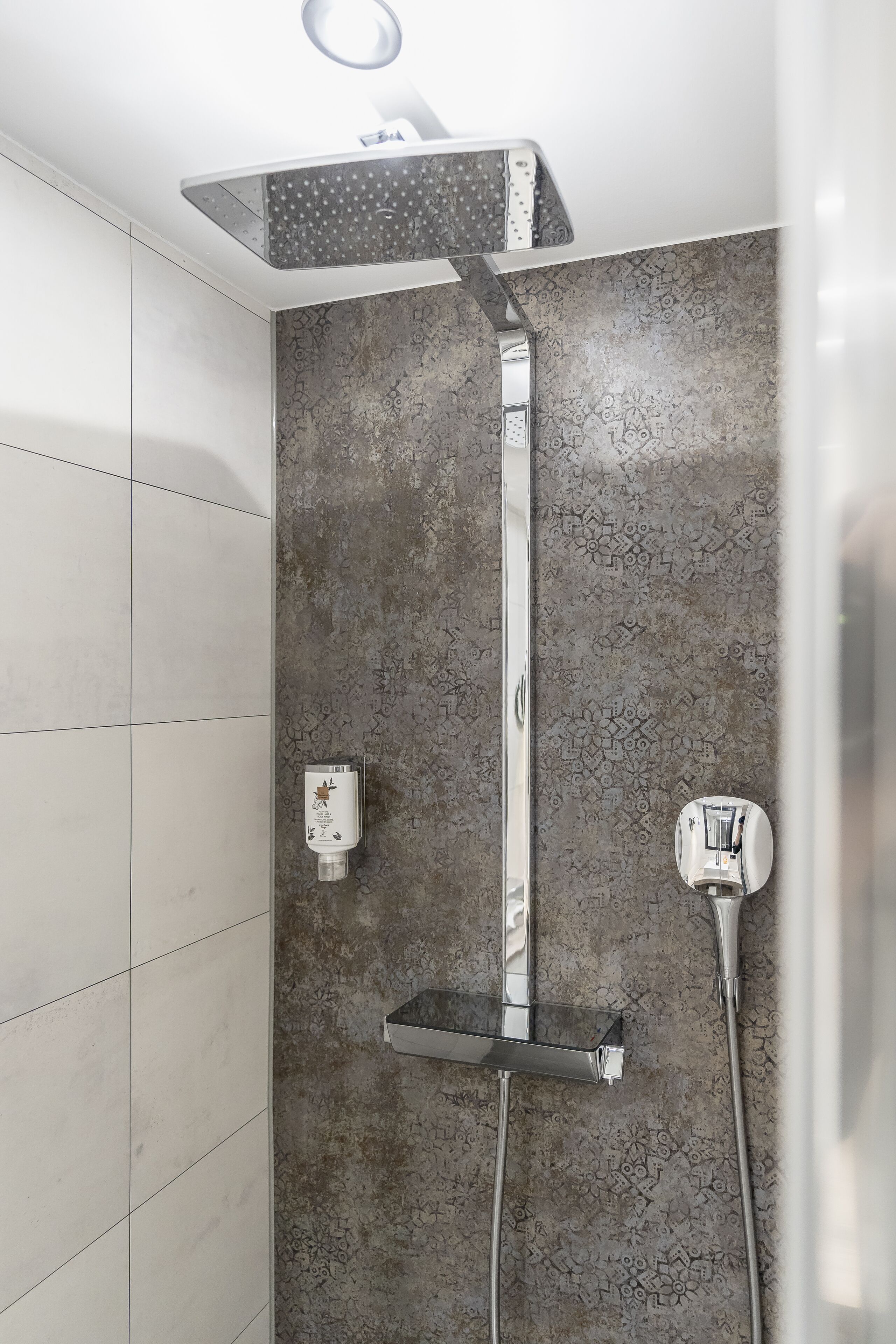A shower with a rain showerhead, a handheld showerhead, and a handheld massager.