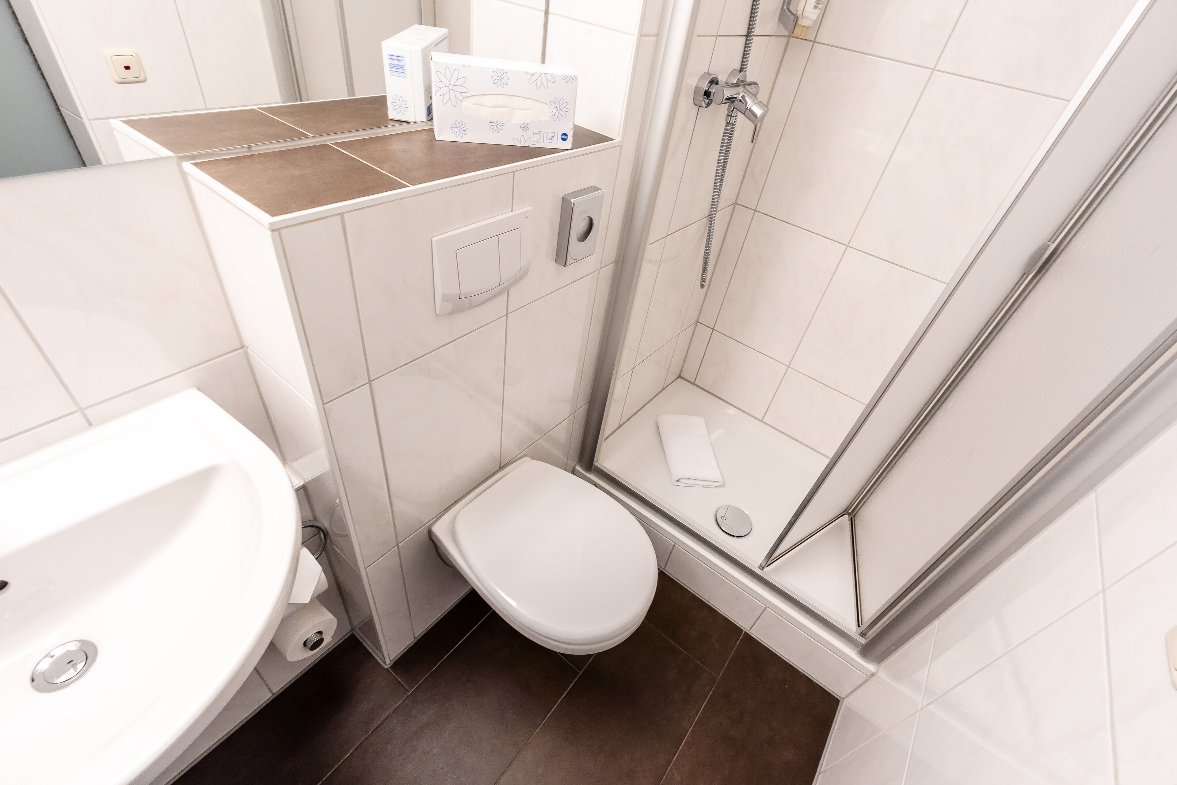 Ein modernes Badezimmer mit Toilette, Waschbecken und Dusche.