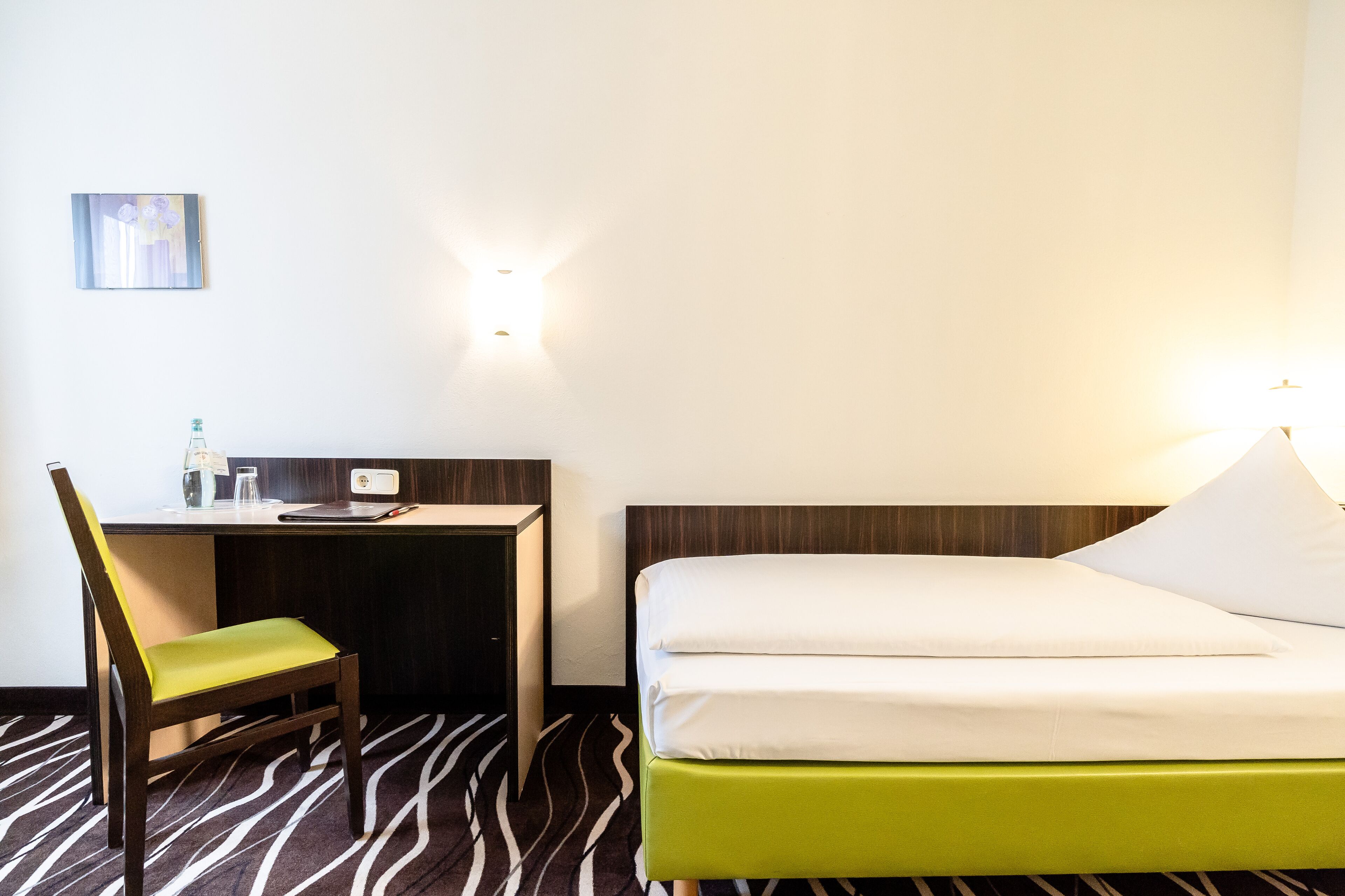 A hotel room with a bed, a desk, and a chair.