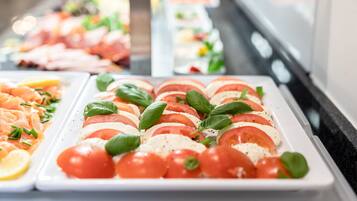 A buffet with various food options including a dish with tomatoes, basil, and cheese.