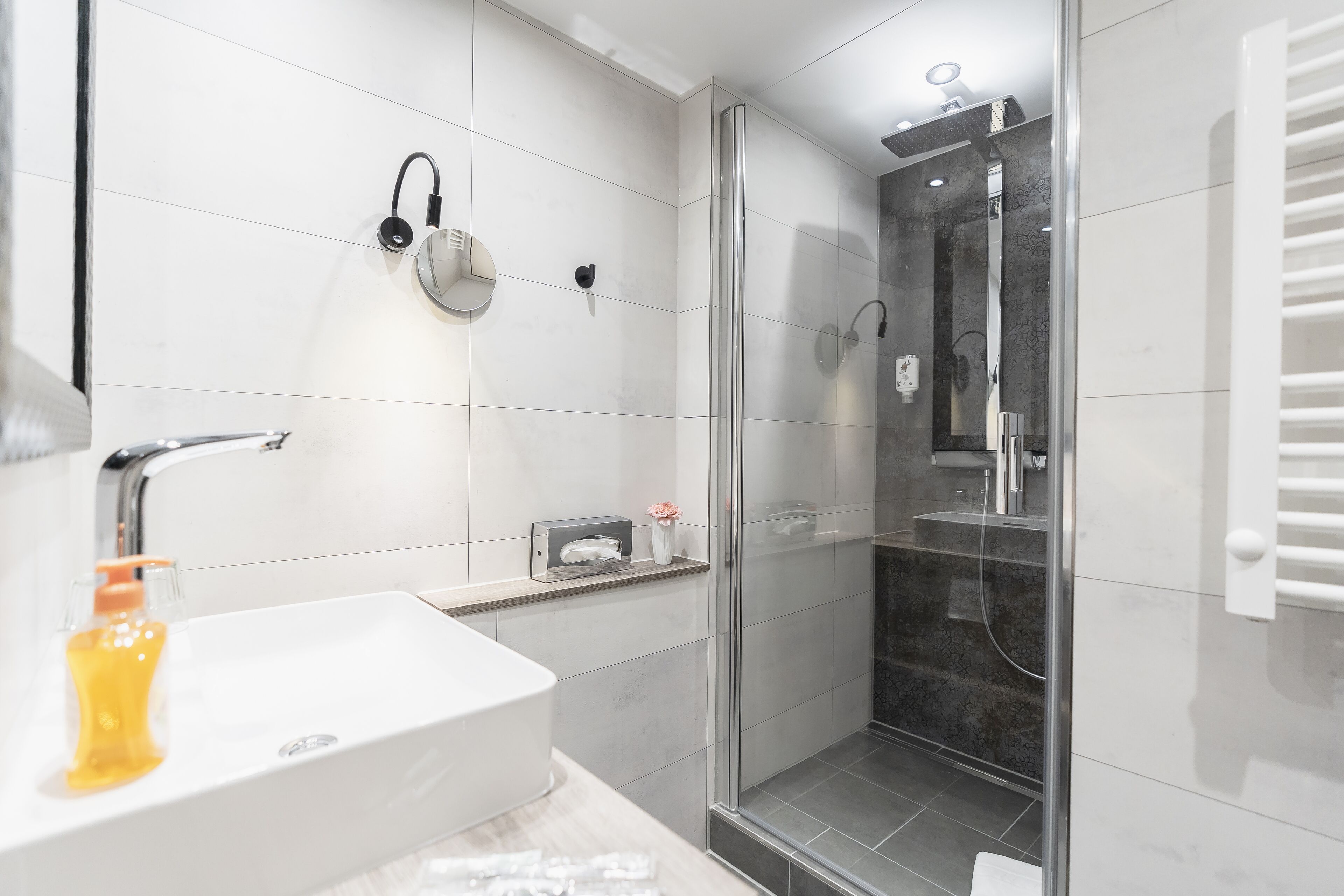 Une salle de bain moderne avec un lavabo blanc, une douche en verre et un porte-serviettes.