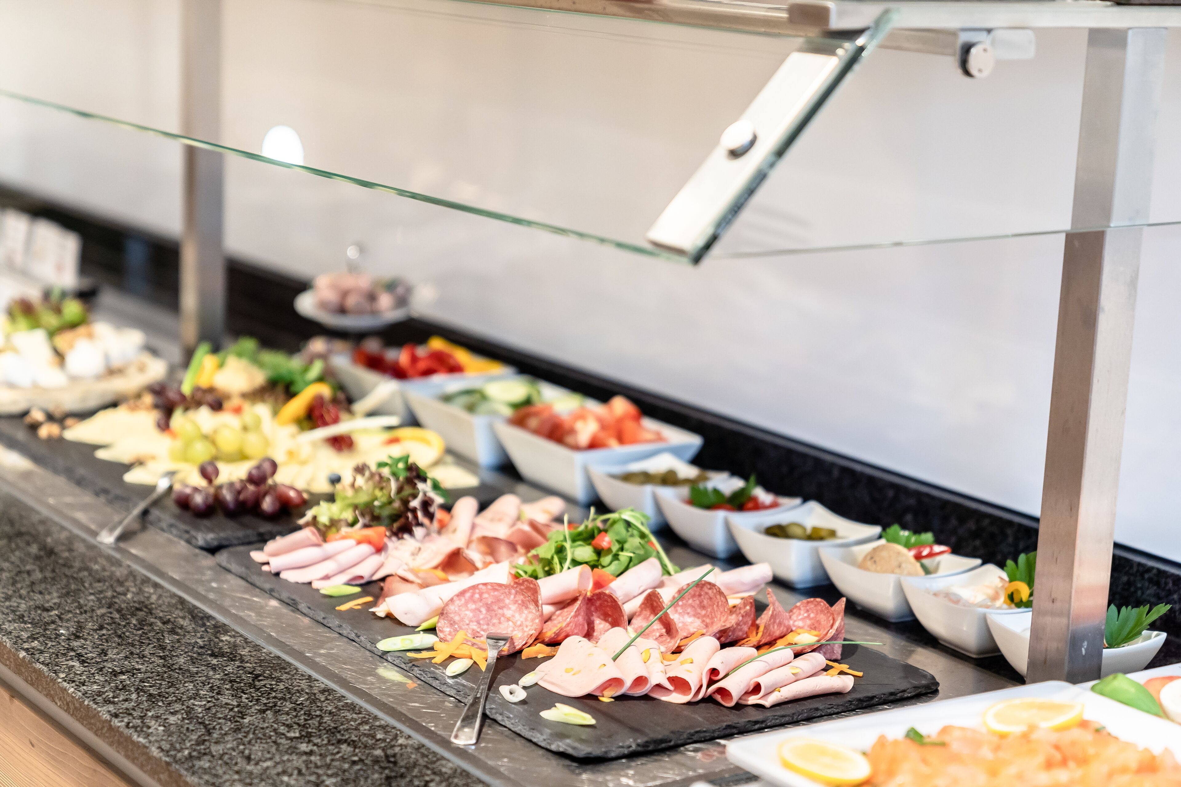 A buffet with various food items including meats, cheeses, and salads.
