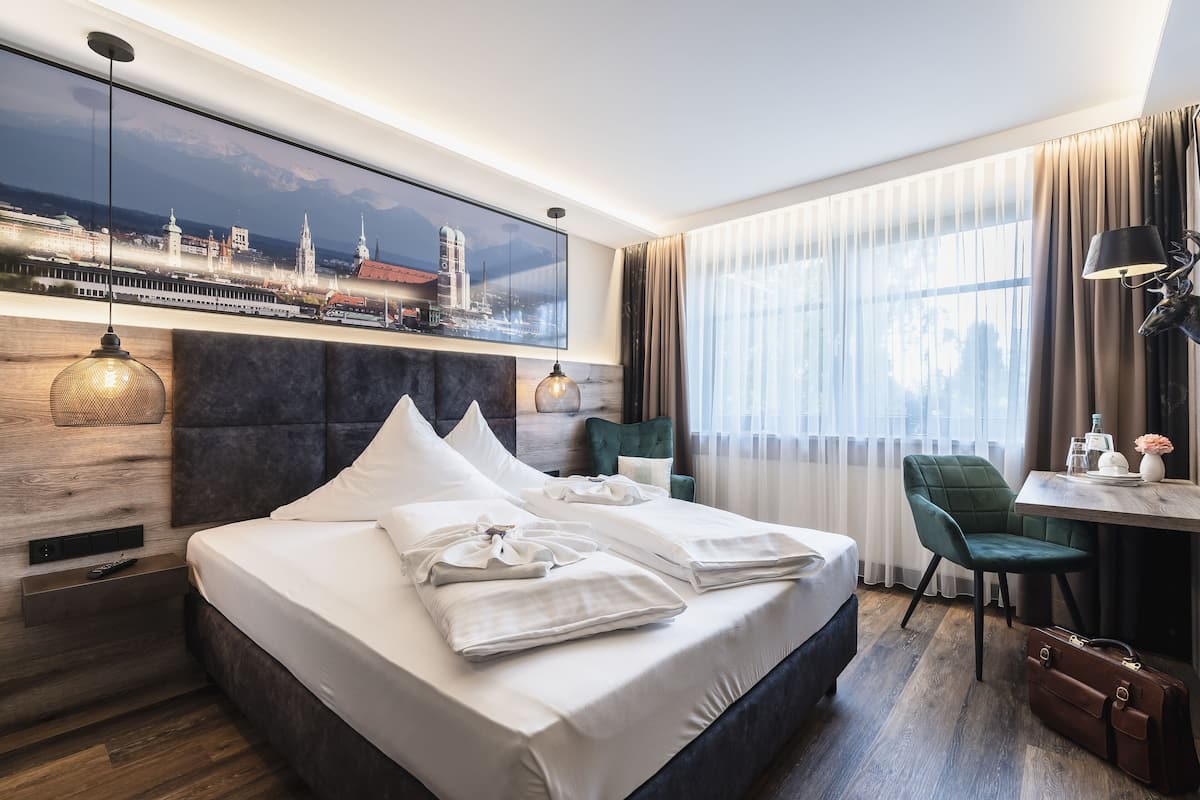A modern hotel room with a large bed, a desk, and a cityscape view.