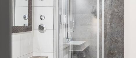 A modern bathroom with a glass-enclosed shower, a white toilet, and a vanity with a mirror.