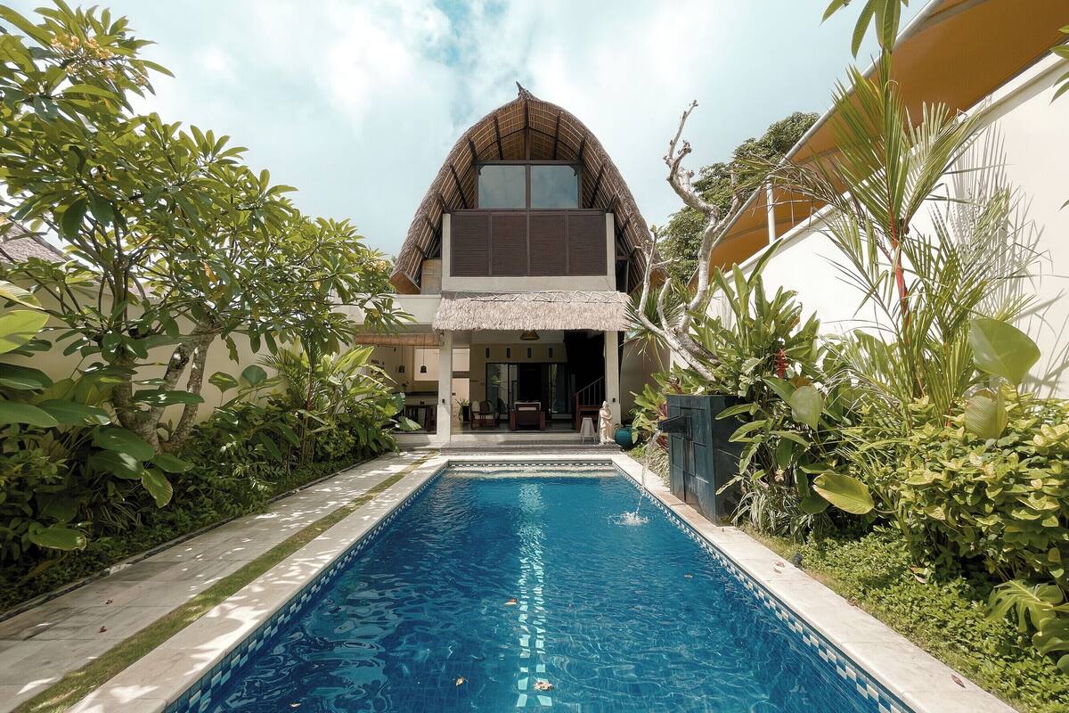 A modern house with a swimming pool surrounded by lush greenery.