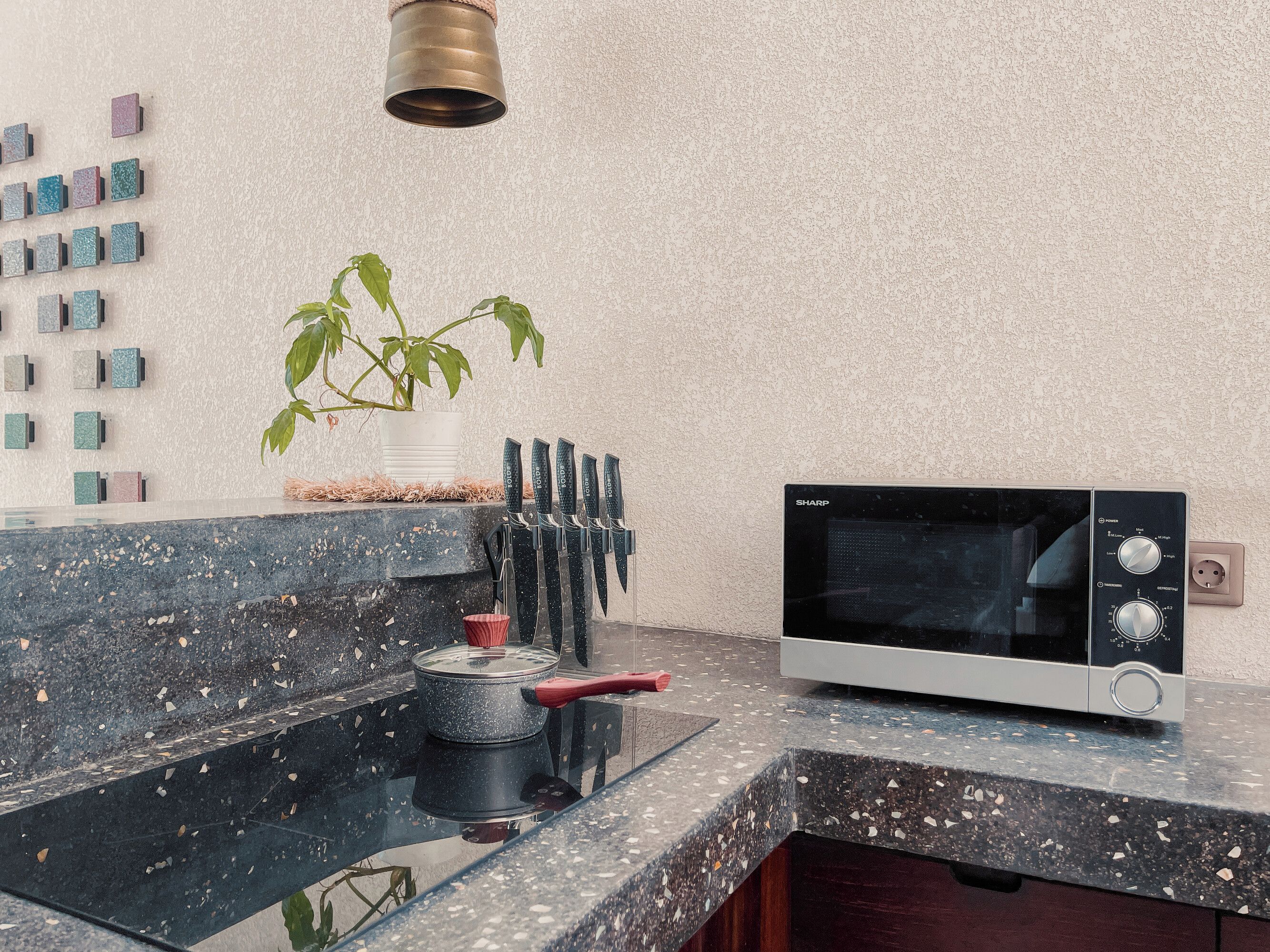 A kitchen with a microwave, a plant, and a set of knives on the counter.