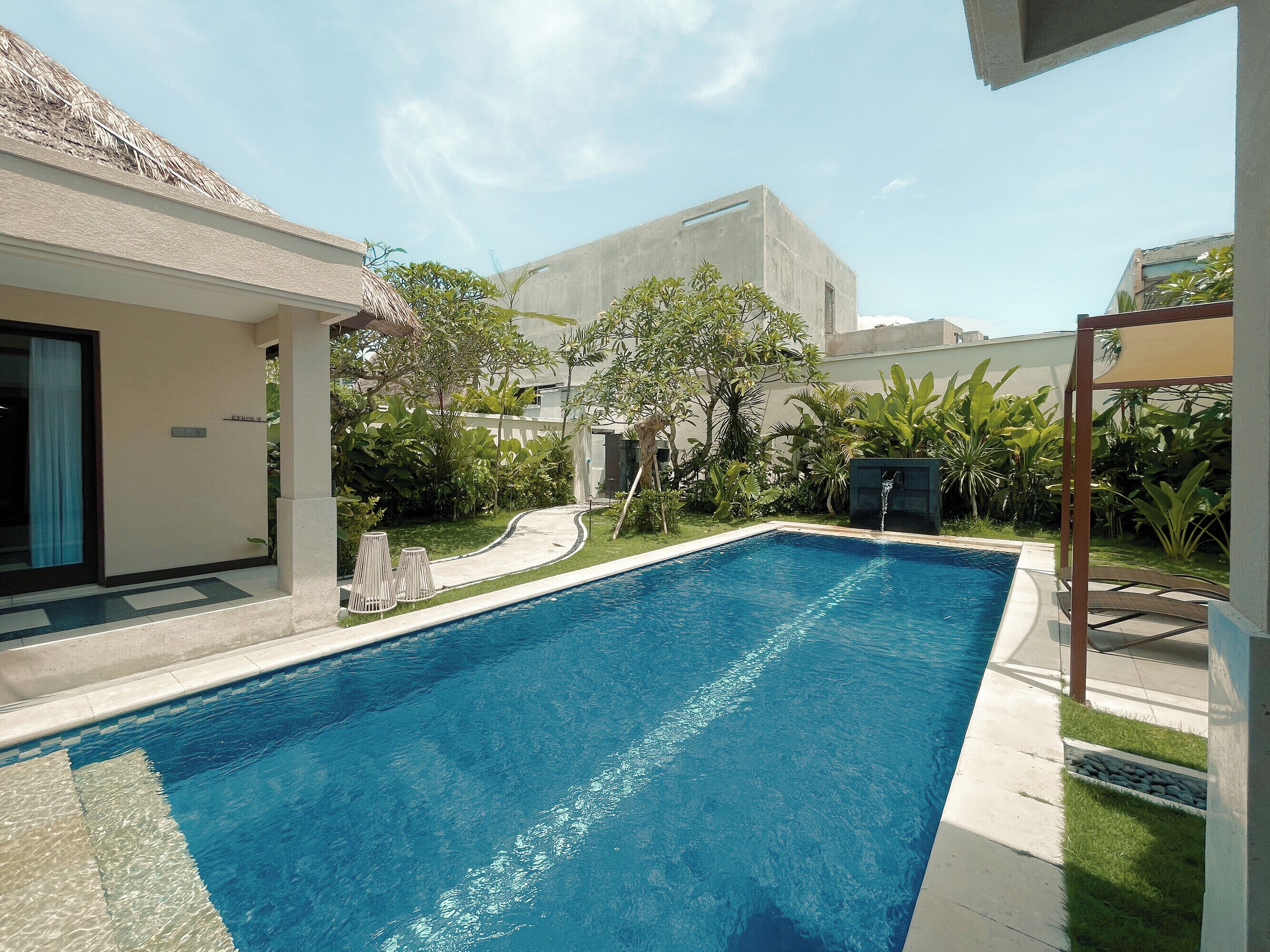 A swimming pool with a clear blue water, surrounded by a well-maintained garden and a modern building.