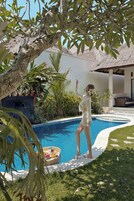 Una piscina al aire libre, sombrillas, sillones reclinables de piscina