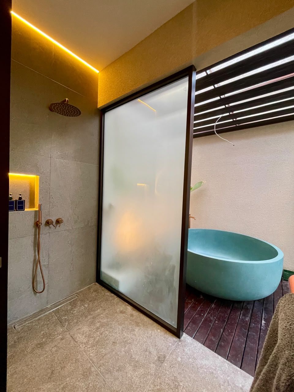 Un baño moderno con cabina de ducha de vidrio, lavamanos empotrado y suelo de madera.