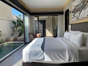 Ein modernes Hotelzimmer mit einem großen Bett, einem kleinen Balkon mit Pool und Blick auf die Umgebung.